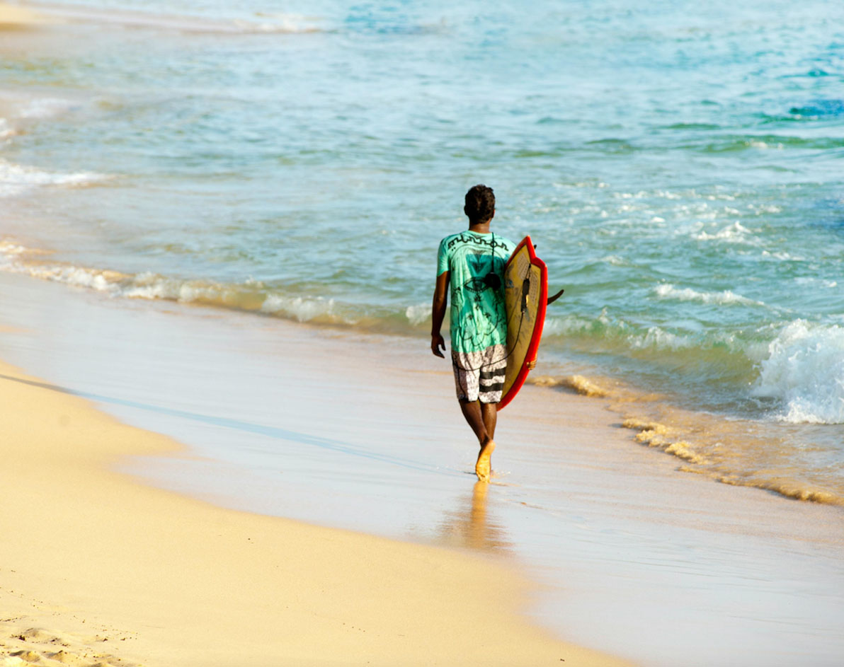 Chico surfista paseando por la playa en Srilanka